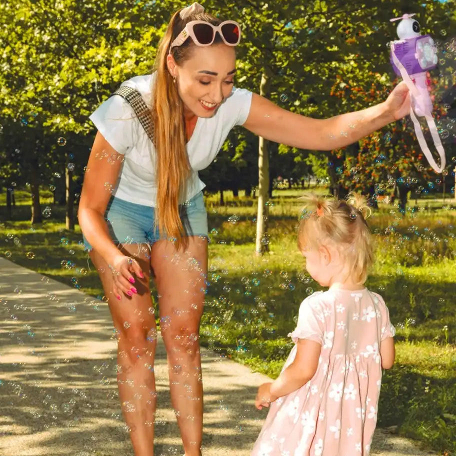 Fetiță care urmărește baloane de săpun în aer liber