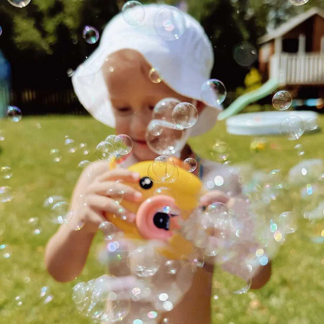 Copil in gradina care priveste bulele produse de aparatul Woopie Puisor.