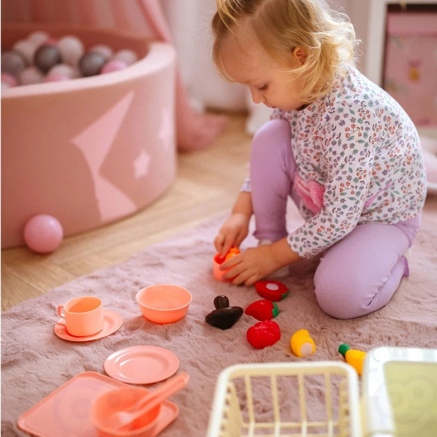 Copil care se joacă pe covor cu accesoriile din setul Woopie Magic Kitchen Sink.