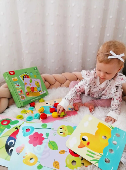 Copil care se joacă cu setul Tooky Toy Pattern Pegs Big și potrivește pinii colorați pe planșe.