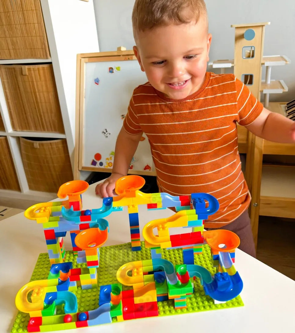 Copil care se joacă la masă cu pista de bile Woopie Crazy Marble Run și urmărește bilele pe traseu.