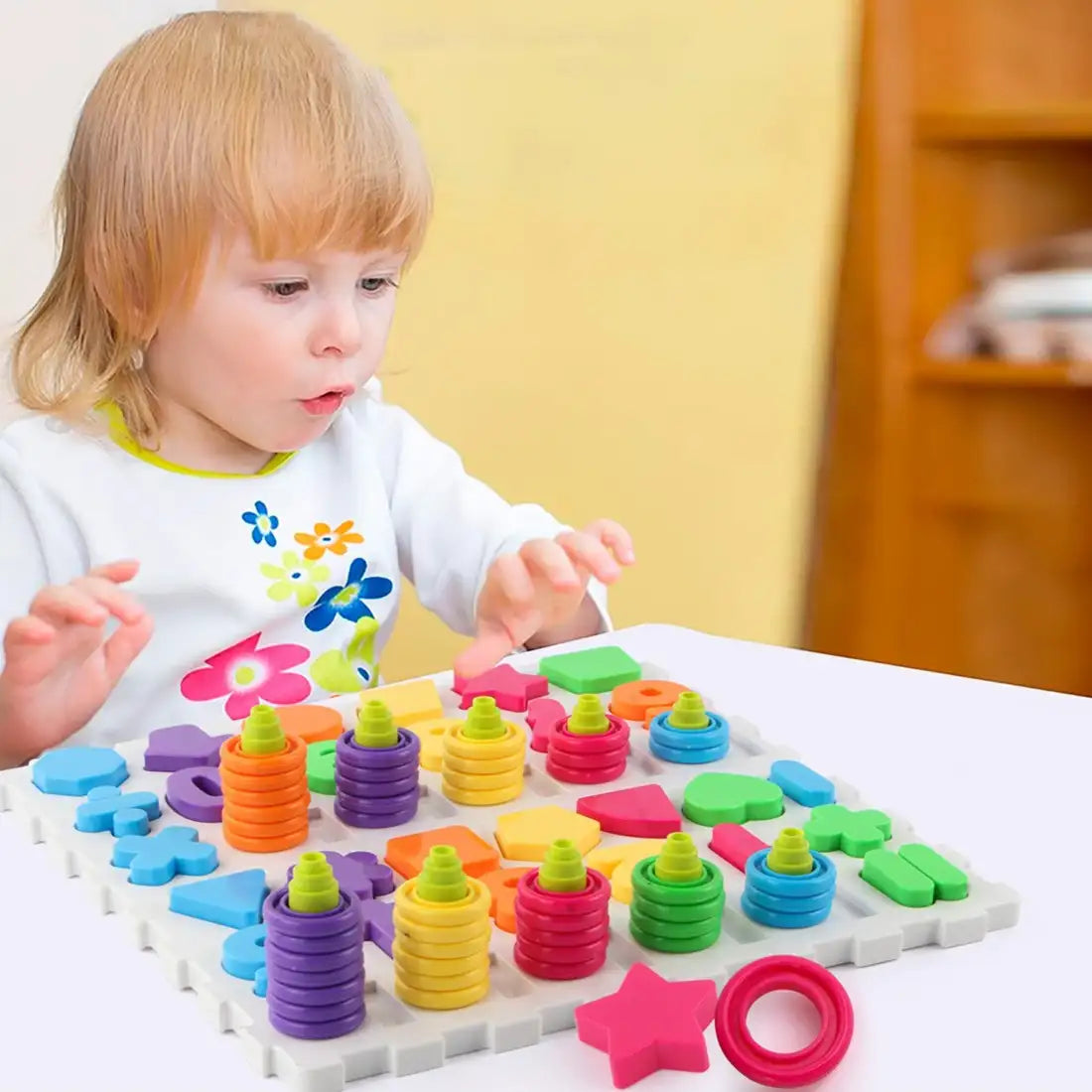 Copil care foloseste jocul de sortare Woopie cu numere, forme geometrice si inele colorate.