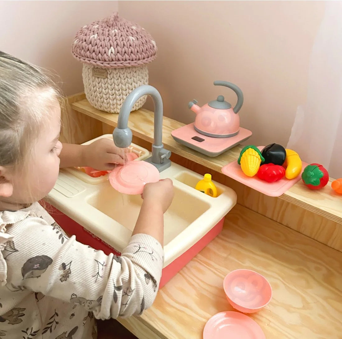 Copil care spală o farfurie la chiuveta de bucătărie Woopie Magic Kitchen Sink.