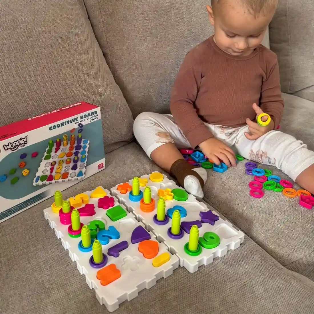 Copil care sorteaza inele colorate pe tabla cognitiva Woopie, joc pentru motricitate fina.