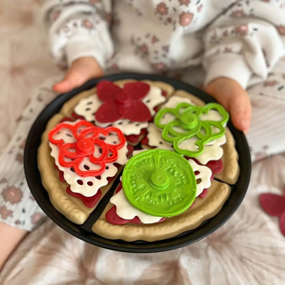 Copil ținând tava cu pizza Woopie asamblată, cu toppinguri colorate pentru joc de rol.