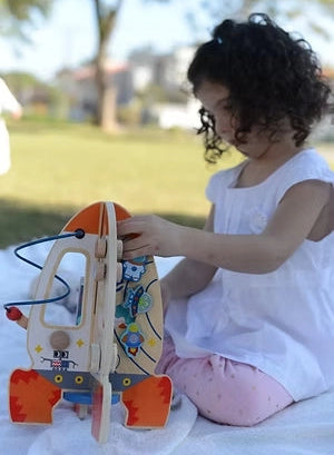 Fetita explorand activitatile rachetei Tooky Toy, cu labirint, abac si elemente mobile.