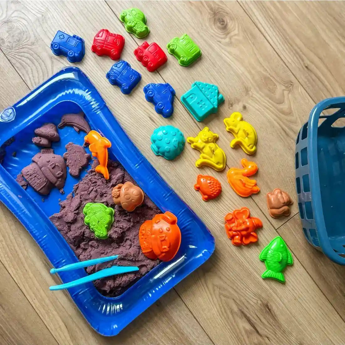 Set Woopie cu nisip kinetic, tăviță albastră, coș și forme colorate pentru animale, vehicule și căsuțe.
