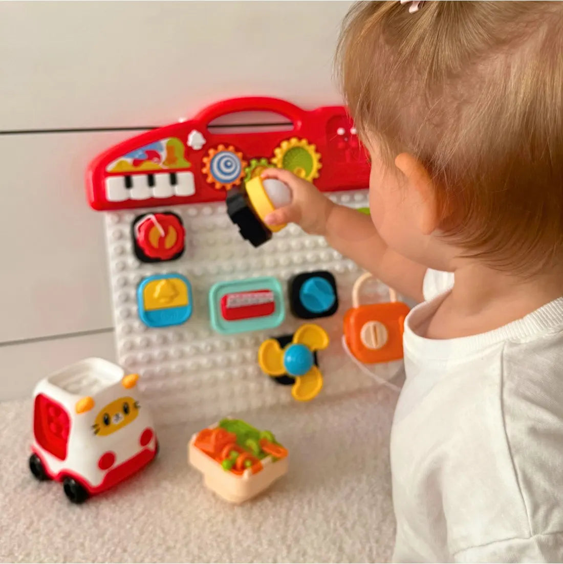 Copil atașând cuburi manipulative Woopie Training Blocks pe panou senzorial.