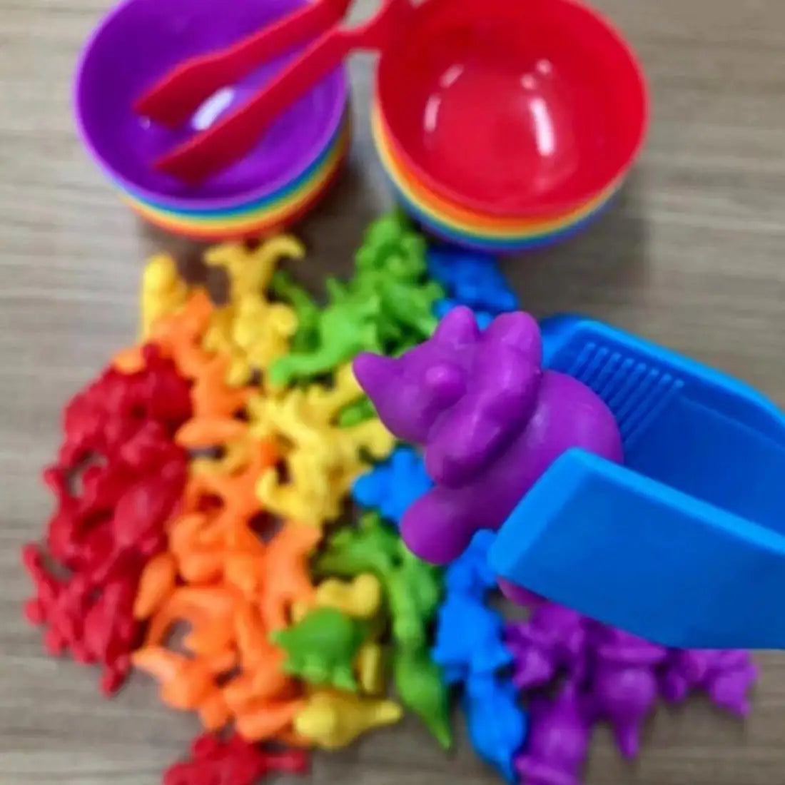 Prim-plan cu penseta care prinde o figurină marină mov din jocul Woopie de sortare culori.