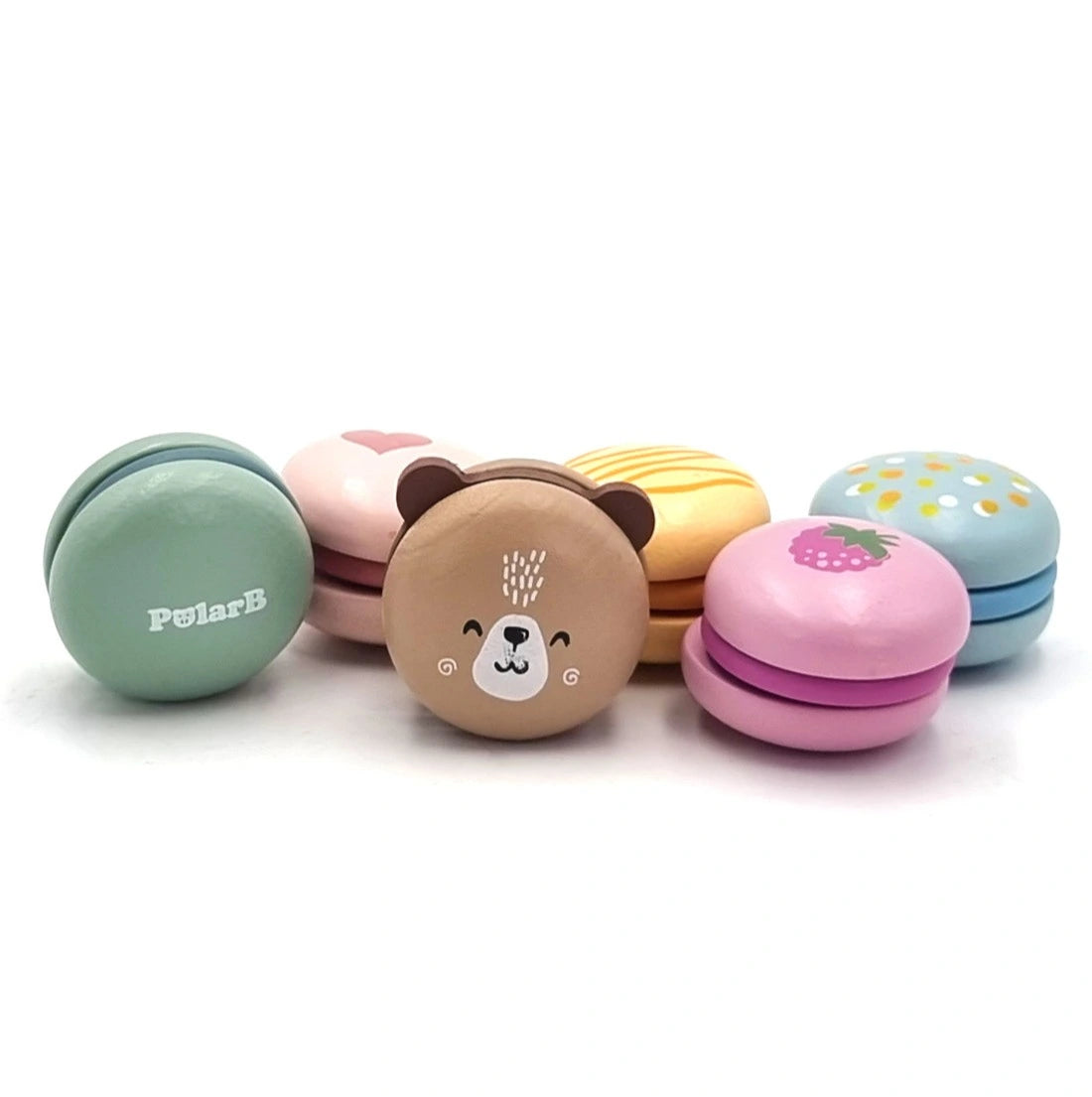 Macarons din lemn PolarB Viga grupate frontal, cu logo, ursuleț, căpșună și modele colorate.