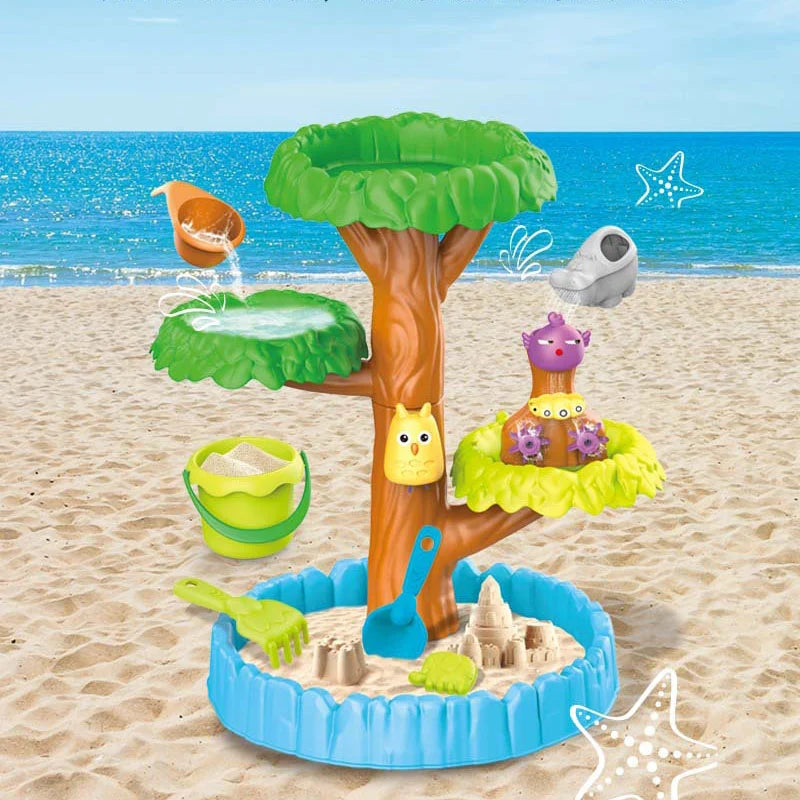 Masa Woopie Big Tree Water Table pe plajă, cu nisip, apă, găletușă și accesorii pentru joacă de vară.