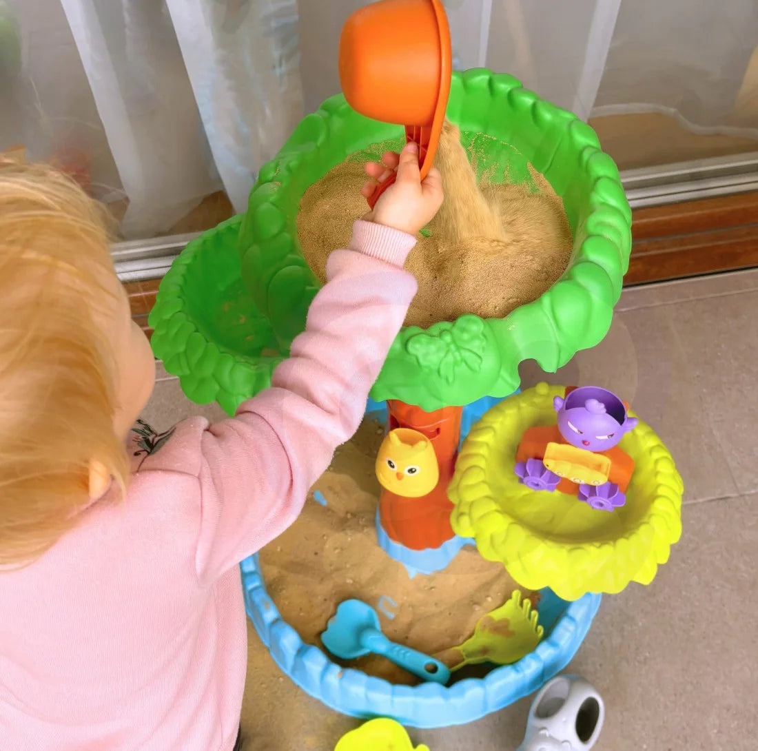 Copil care toarnă nisip în masa de joacă Woopie Big Tree Water Table, cu copac, tăvi și accesorii