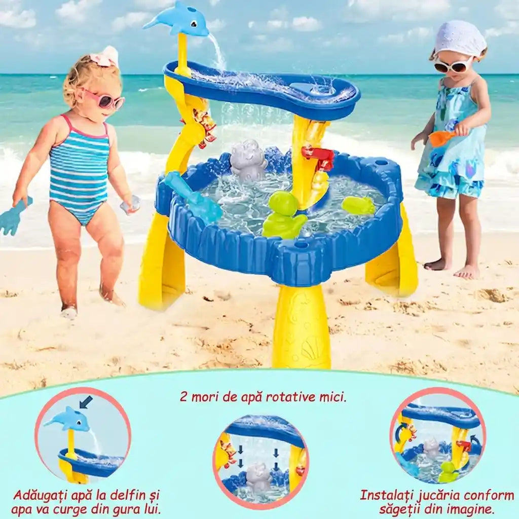 Masă Woopie cu delfin pe plajă, cu instrucțiuni vizuale pentru turnarea apei și roți rotative.