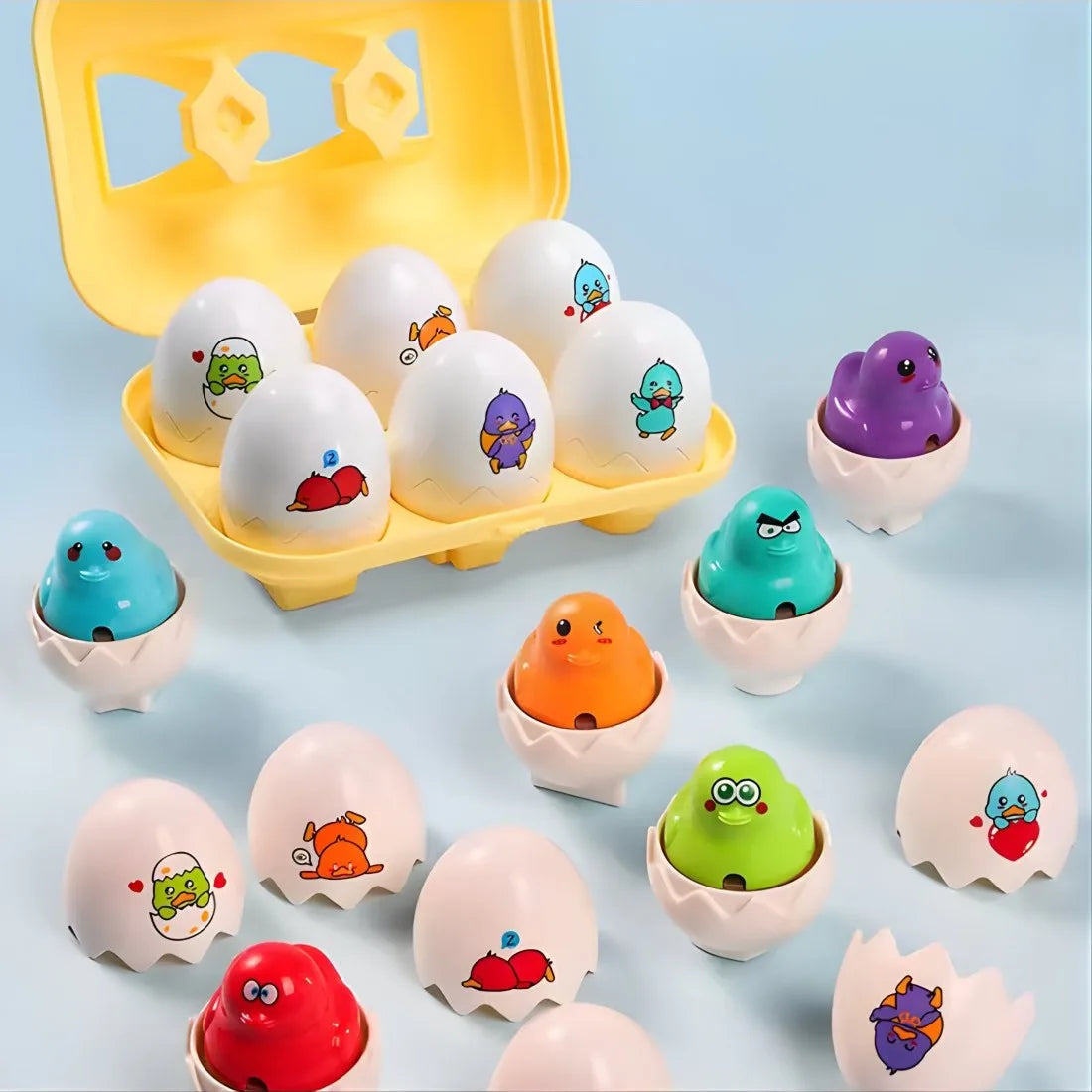 Set complet Woopie cu 6 ouă cu puișori, cutie galbenă și puișori colorați pe fundal albastru.