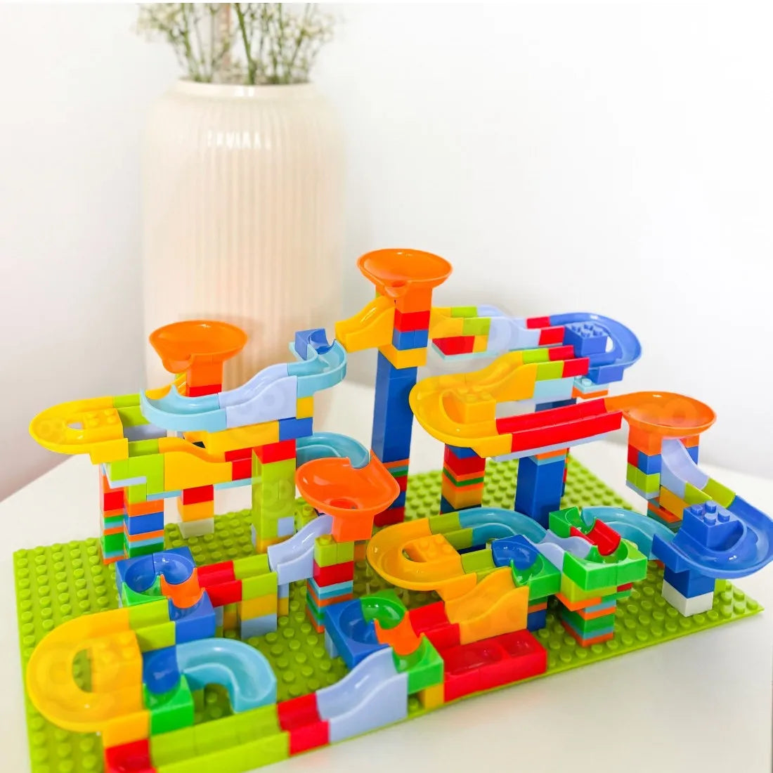 Pistă cu bile Woopie Crazy Marble Run asamblată pe bază verde, cu pâlnii portocalii și trasee colorate.