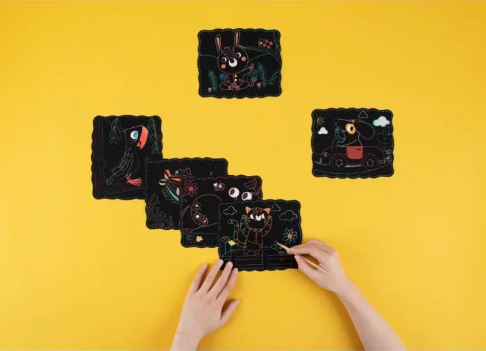 Copil care foloseste plansele Woopie Scratch Paper Art pe masa galbena, cu betisor din lemn.