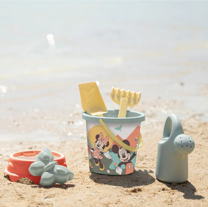 Setul Smoby Life Mickey și Minnie așezat pe nisip, cu găletușă, stropitoare și accesorii pentru joacă la plajă.