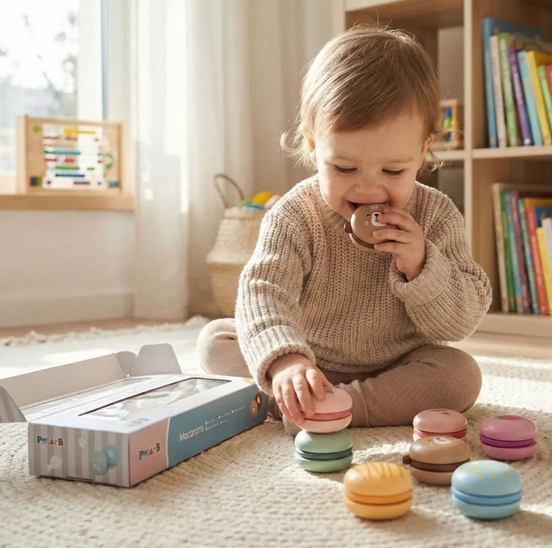 Copil mic care se joacă pe covor cu macarons din lemn PolarB Viga și cutia produsului deschisă.