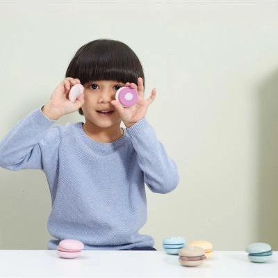 Copil care ține două macarons din lemn PolarB Viga la ochi, într-un joc de sortare și imaginație.